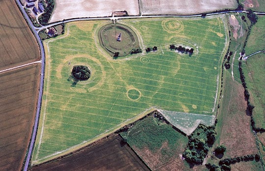 An aerial photograph of Knowlton earthworks seen from the north-east, showing the henge and church as well as crop marks of many ploughed out buried features