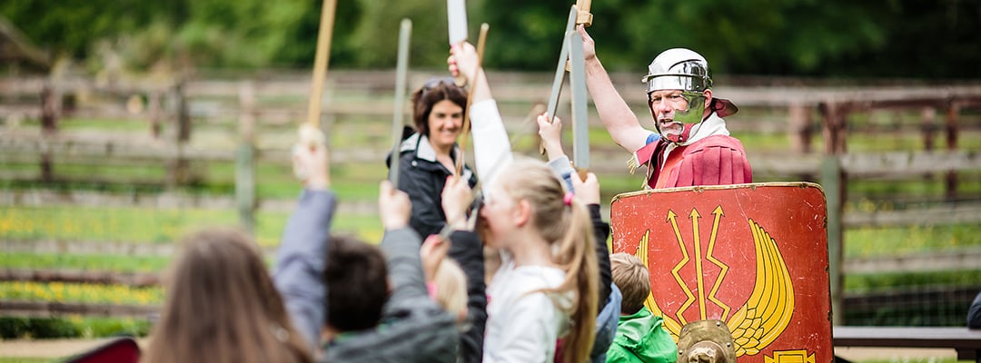 A Roman soldier holds his sword aloft, encouraging children to participate