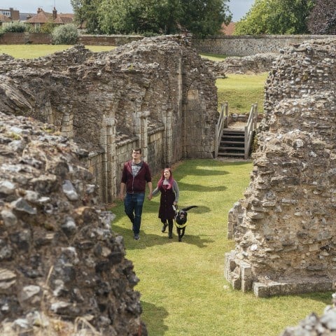 Photo of two people and an assistance dog walking through the ruins of St Augustine's Abbey in Canterbury, Kent