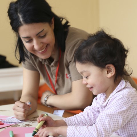Photo of a young child colouring in with an English Heritage staff member supervising
