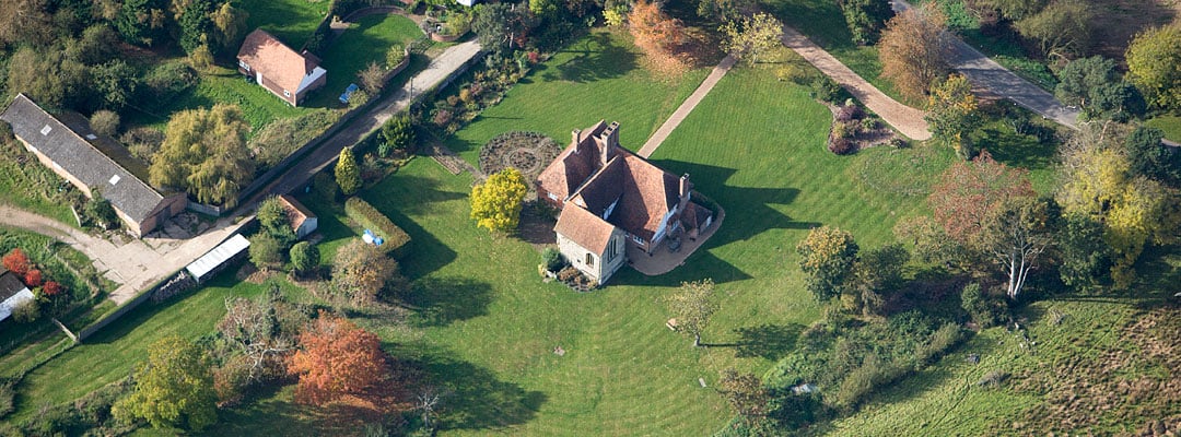 Aerial view of Hornes Place Chapel and the attached manor house in a mature garden landscape