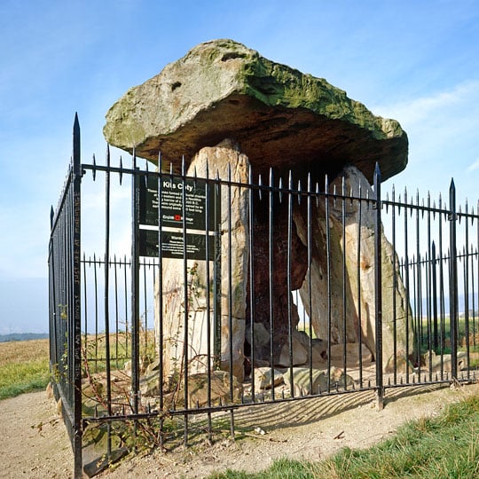 The burial chamber at Kits Coty House, surrounded by a protective black iron railing enclosure