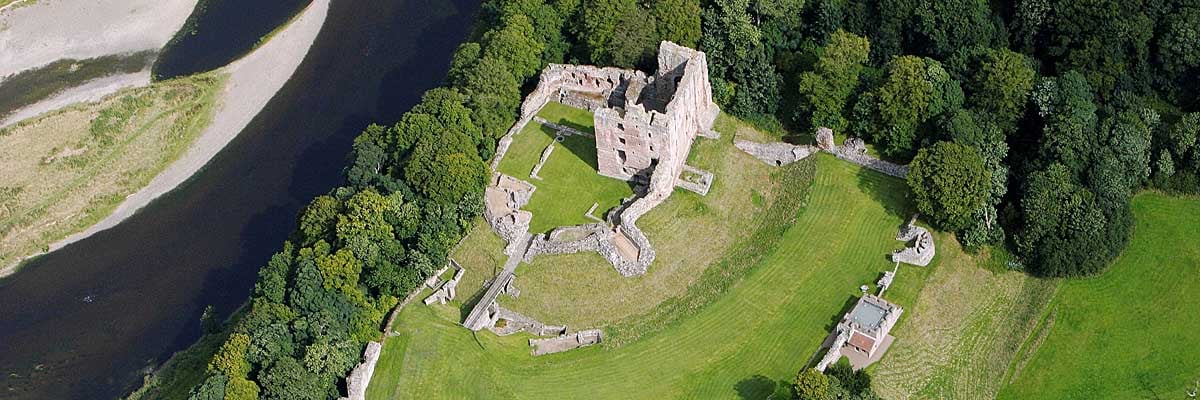 Norham Castle, dominated by its great tower, stands in a commanding defensive position beside the river Tweed