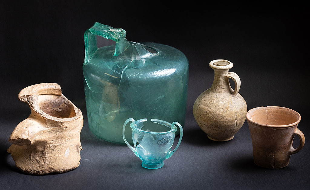 Looking from left to right here shows an amphora neck, a glass bottle, a glass banqueting cup for wine, a flagon and a tankard