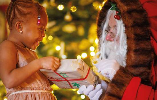 Photo of Father Christmas handing a wrapped gift to a smiling young child Photo of Father Christmas handing a wrapped gift to a smiling young child
