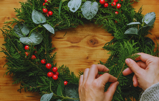 Bird's-eye-view photo of two hands making a Christmas wreath Bird's-eye-view photo of two hands making a Christmas wreath