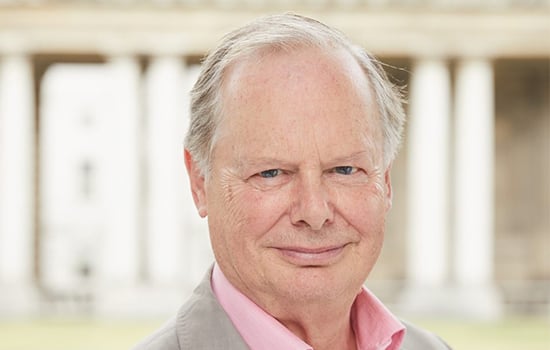 A man (Tony Hales) in pink shirt and white jacket smiles at the camera
