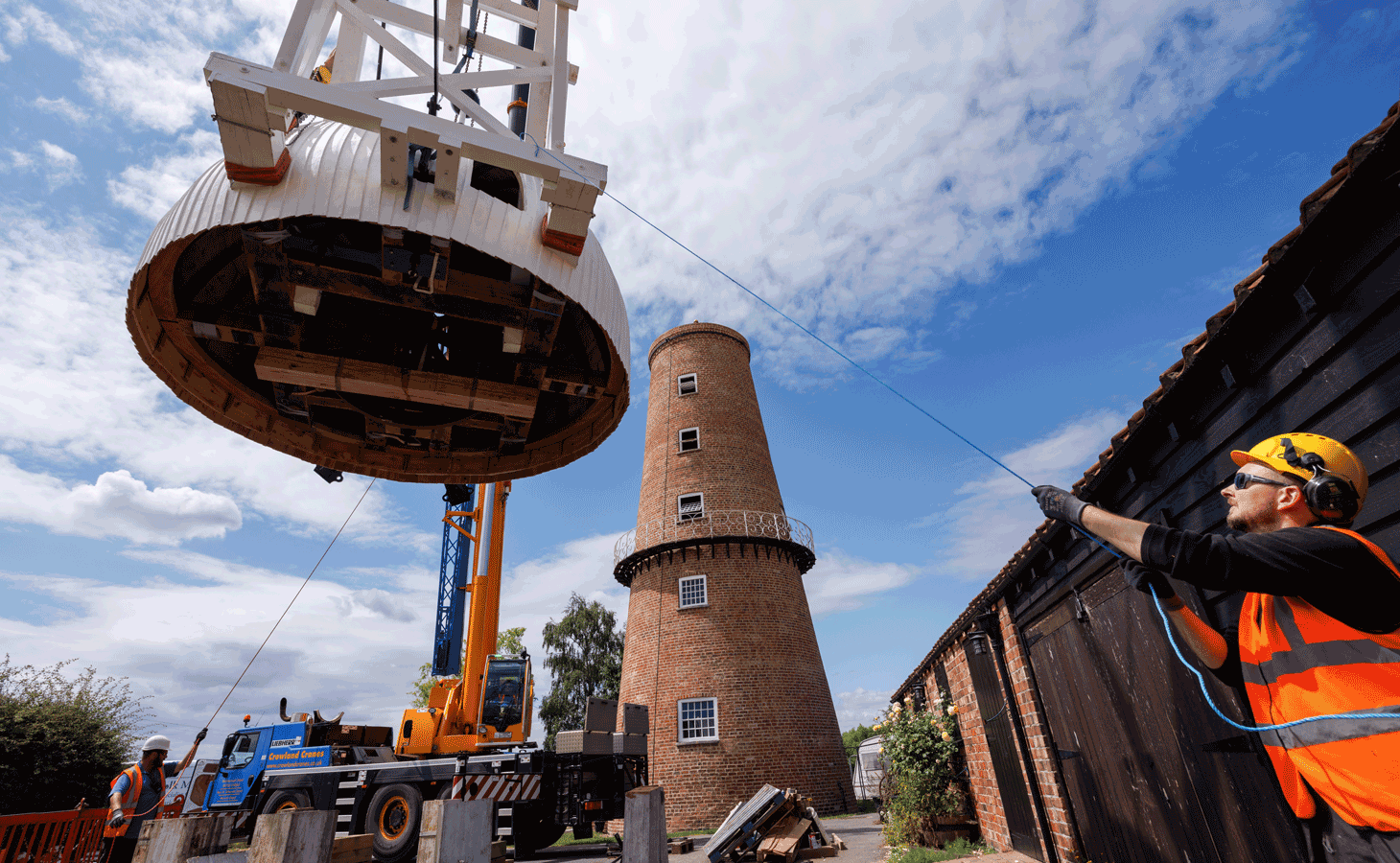 Image: a crane lifts the cap onto the top of the mill