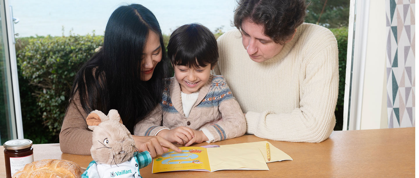 Two adults and a child look through a booklet while smiling
