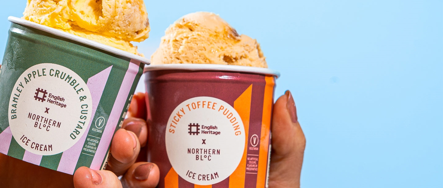 Close up of a tub of Bramley Apple Crumble & Custard ice cream next to a tub of Sticky Toffee Pudding flavour ice cream