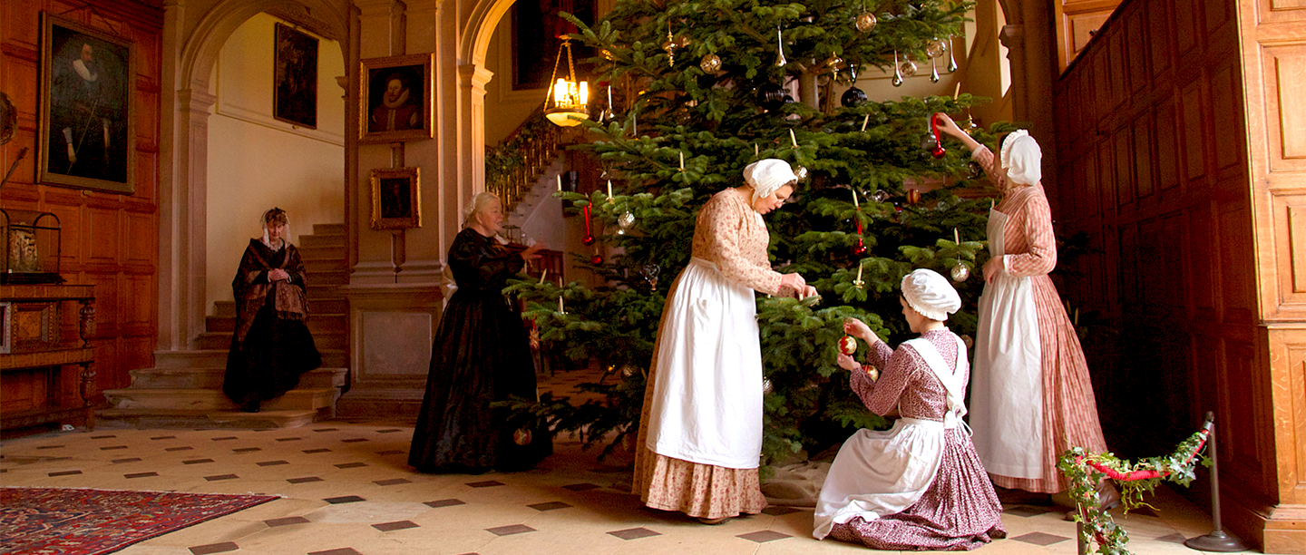 Image: re-enactors dressed as Victorian servants decorate a Christmas tree