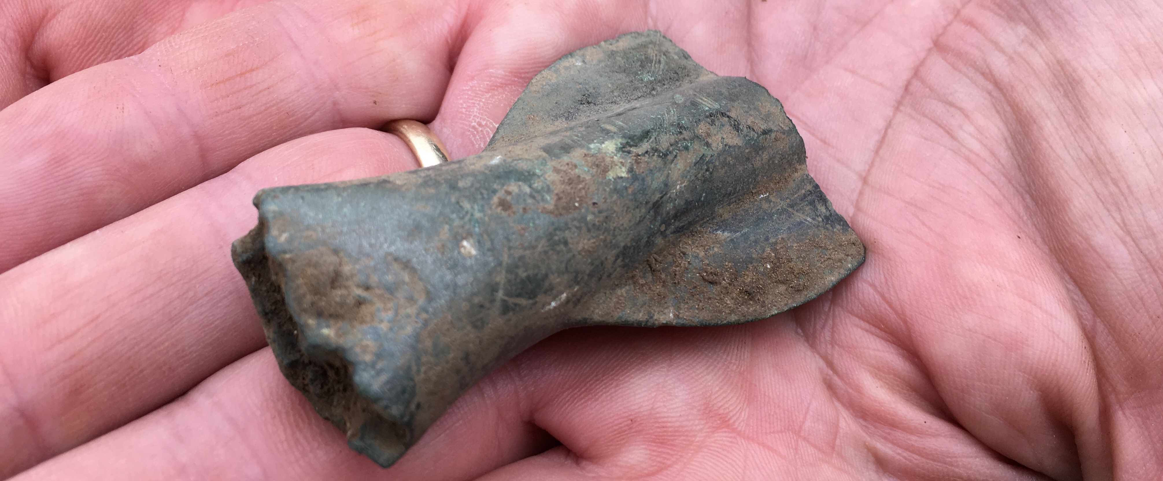 A metal spearhead sitting in the palm of someone's hand.