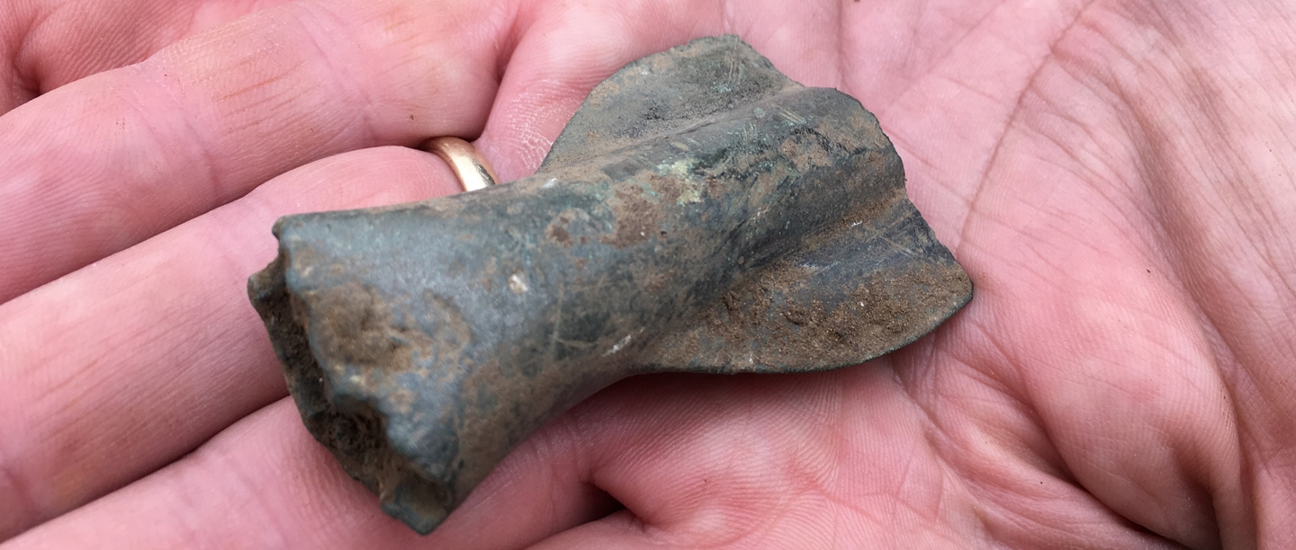 A metal spearhead sitting in the palm of someone's hand.