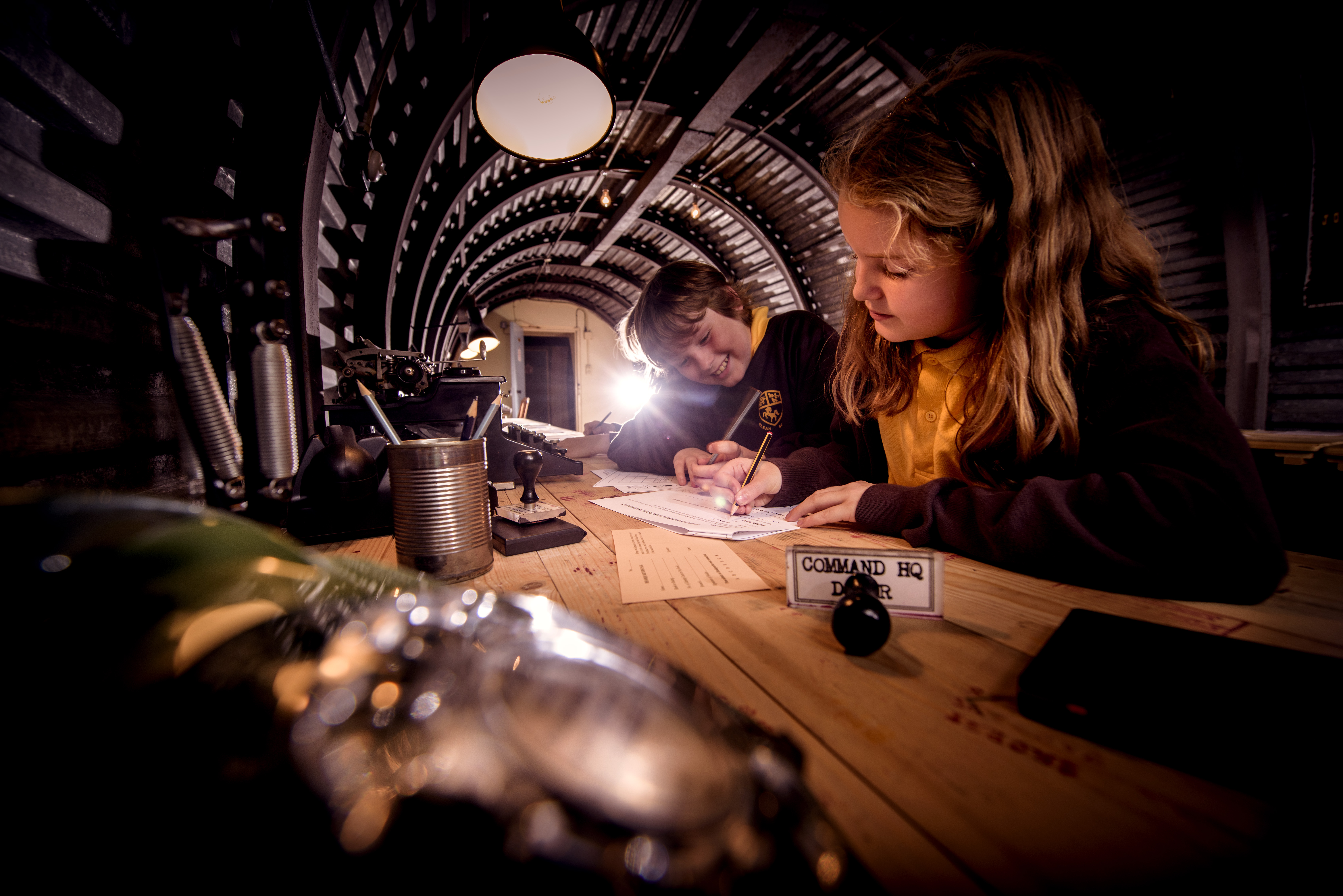 Two girls sit at a typewriter inside the Secret Wartime Tunnels at Dover Castle