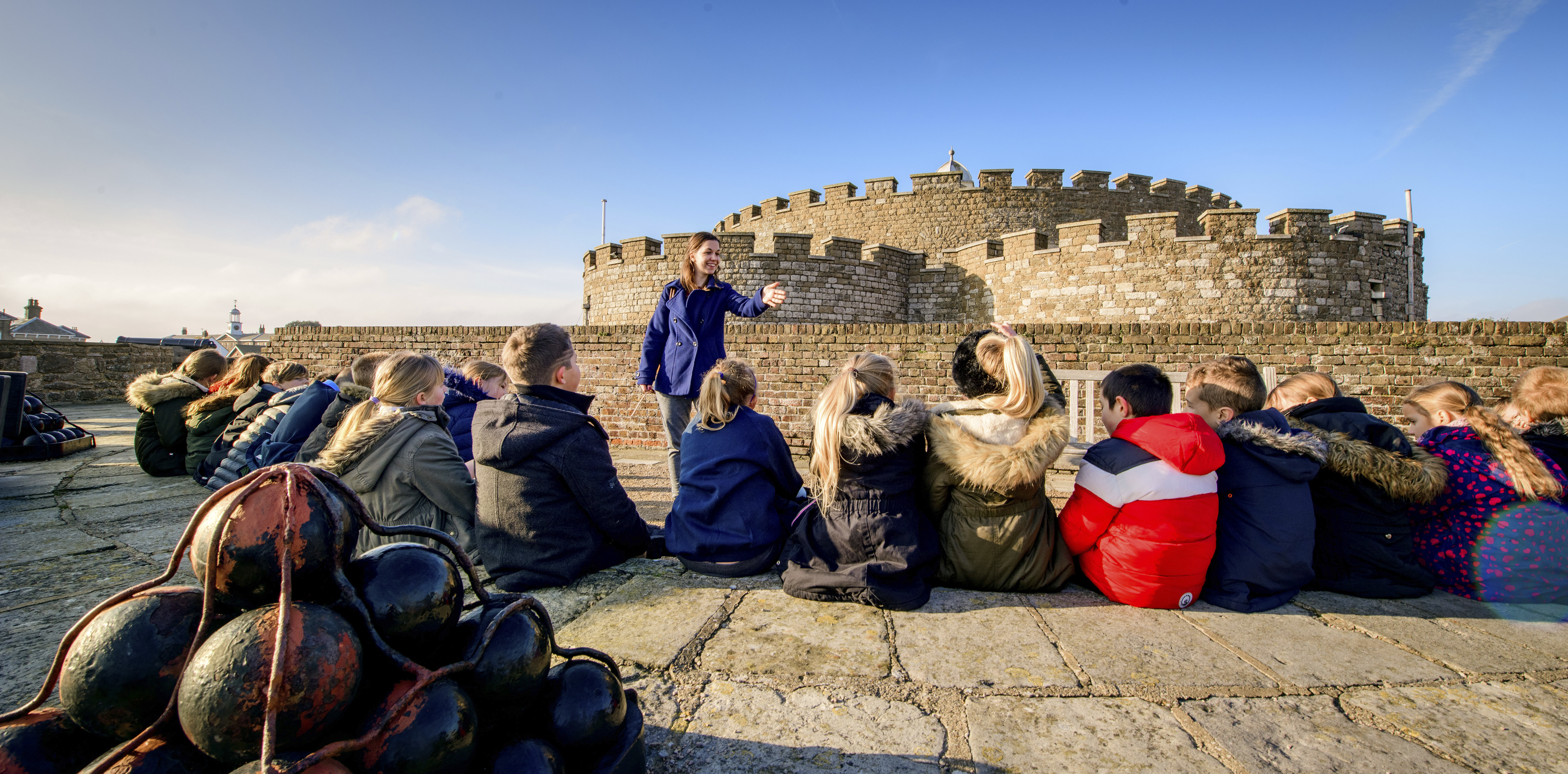 Teacher addresses a large group of students in front of Deal Castle