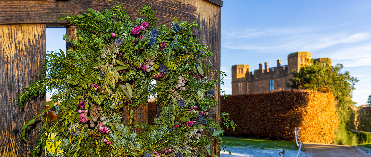 A Christmas wreath hung on a wooden gate outside Kenilworth Castle gatehouse.