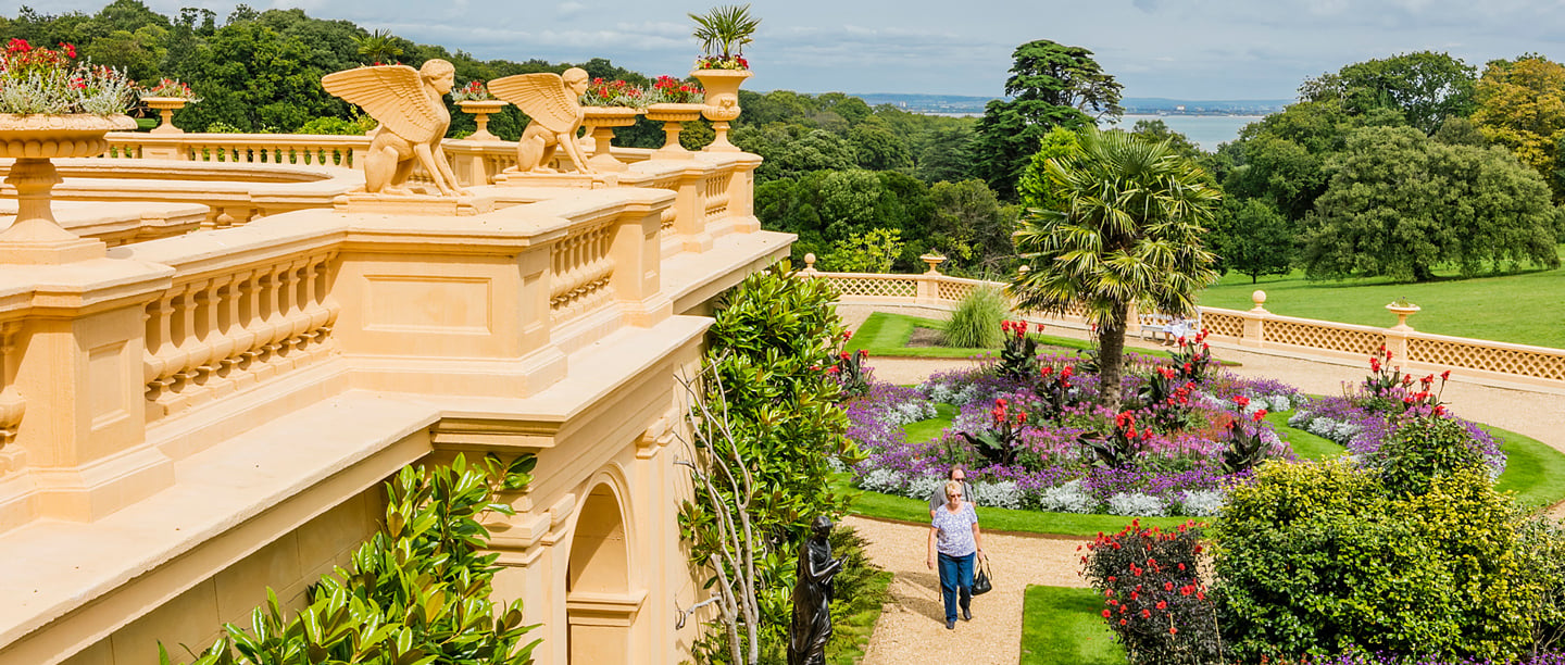 A view of Osborne, taken from the roof showcasing the gardens with two women walking through them on a sunny day.