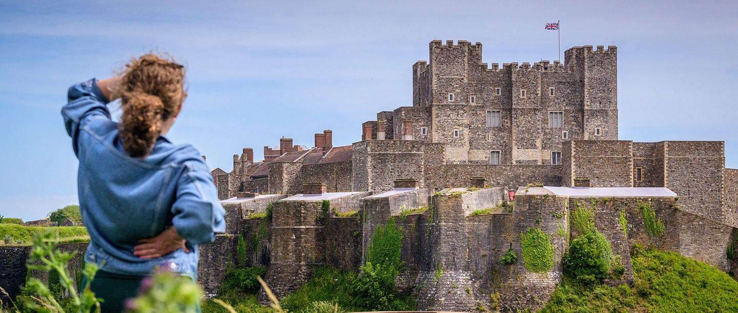 A woman looks over at Dover Castle on a sunny day.