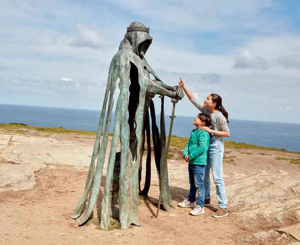 Children looking at the Gallos statue at Tintagel in Cornwall