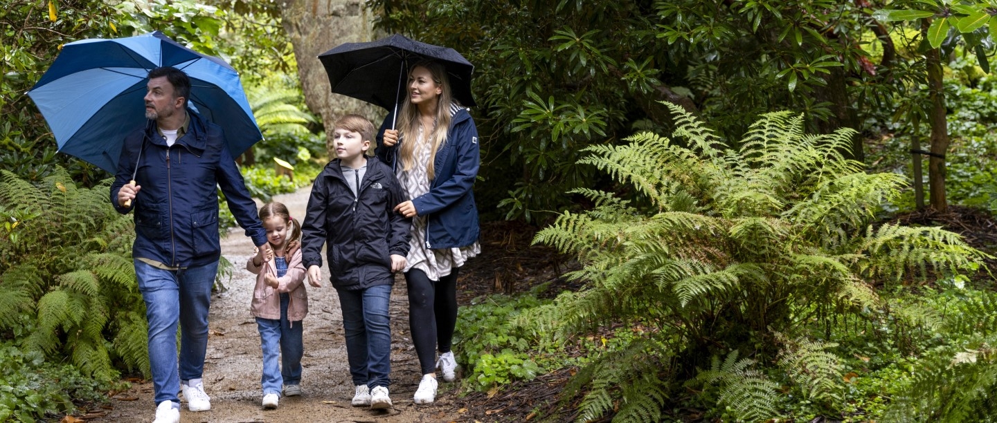 Image: Photo of two parents and two children walking through the leafy Quarry Gardens at Belsay Hall, Castle and Gardens in Northumberland