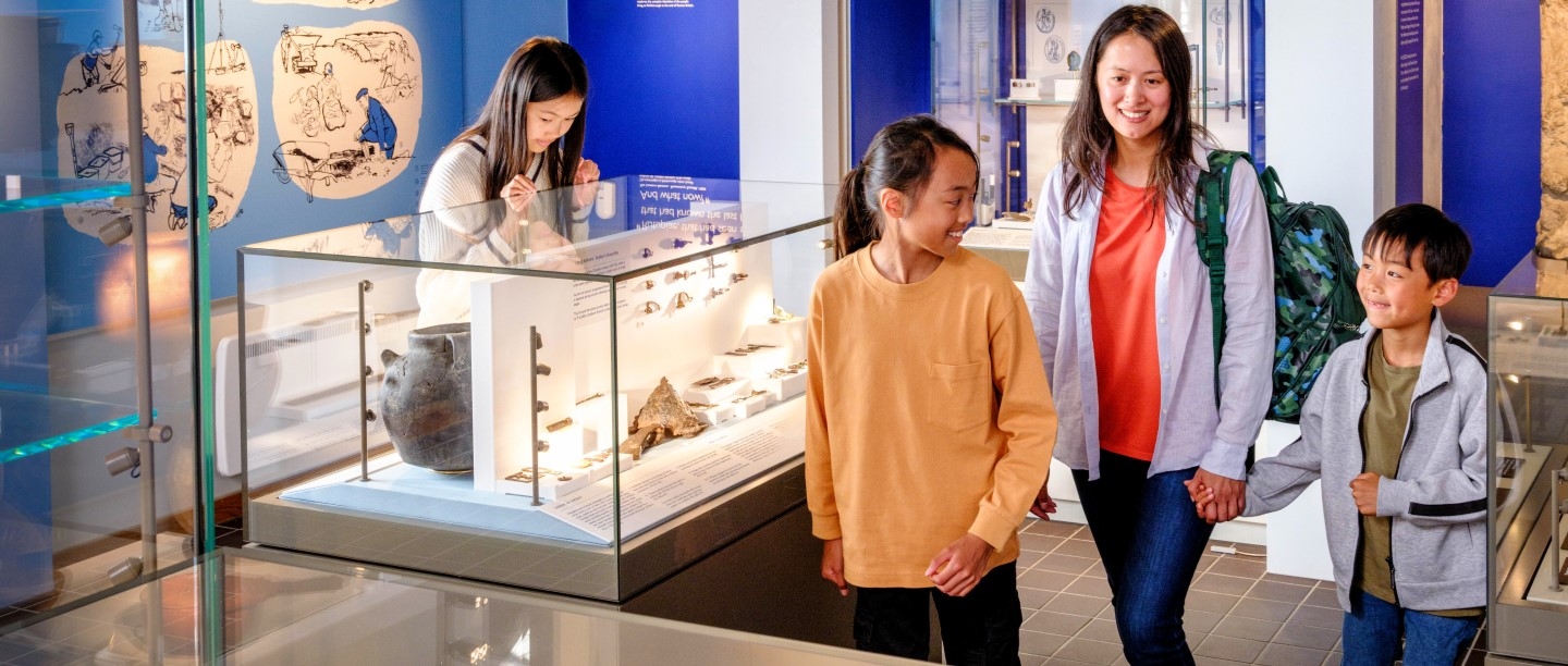 Image: Photo of a parent and their three children exploring the museum at Richborough Roman Fort