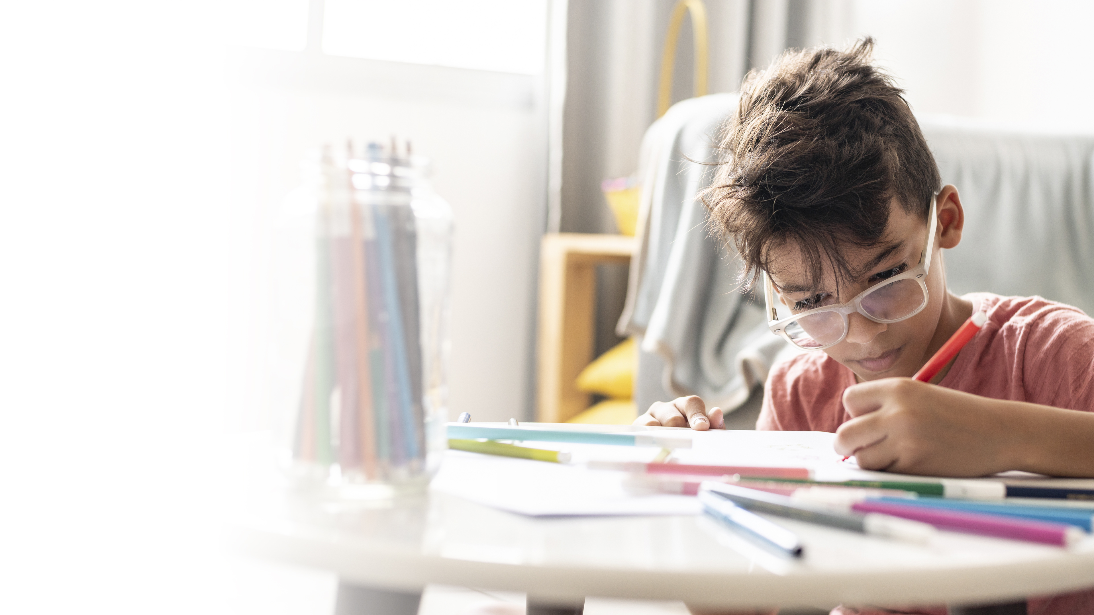 Image: Boy with glasses drawing with coloured pens