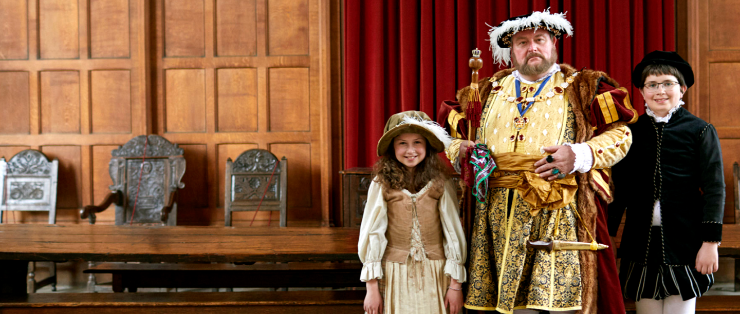 Image: A re-enactor playing Henry VIII with a girl and a boy dressed in Tudor style clothing