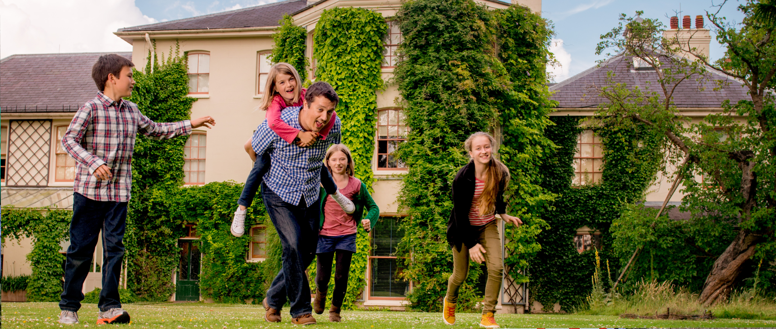 Image: a family run together on the grass in front of Down House, Kent