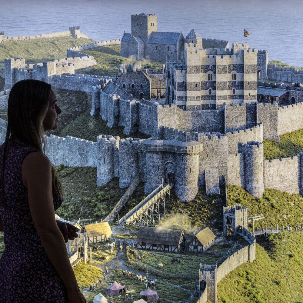 Photo of someone looking at large screen showing a digital recreation of Dover Castle in the medieval period