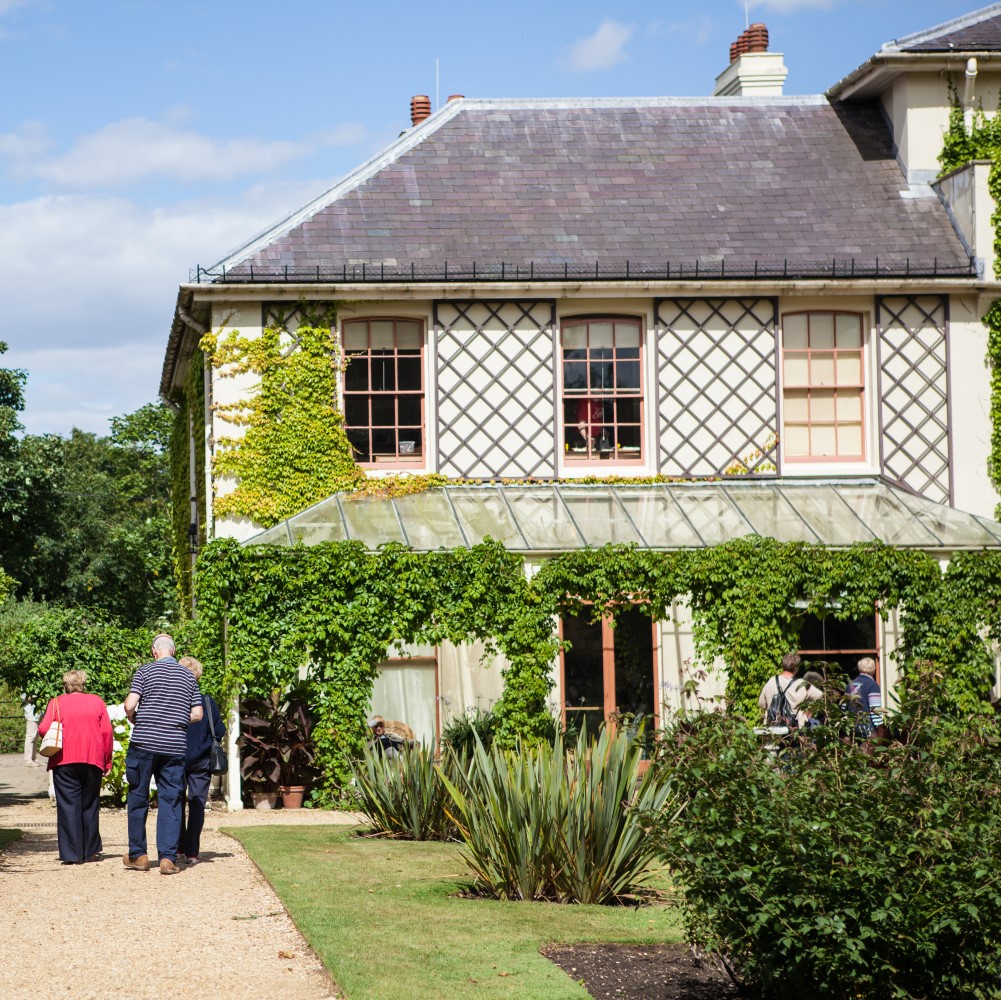 Photo of groups of people walking around the outside of Down House on a sunny day