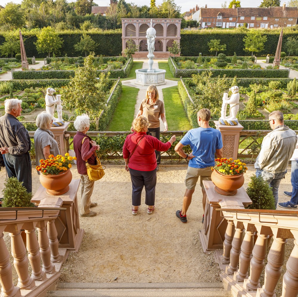 Photo of an English Heritage volunteer speaking to a group of visitors overlooking the Elizabethan Garden at Kenilworth Castle