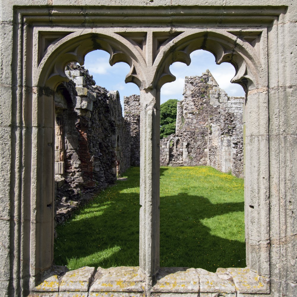 Photo looking through the window of the remains of Haughmond Abbey on a sunny day