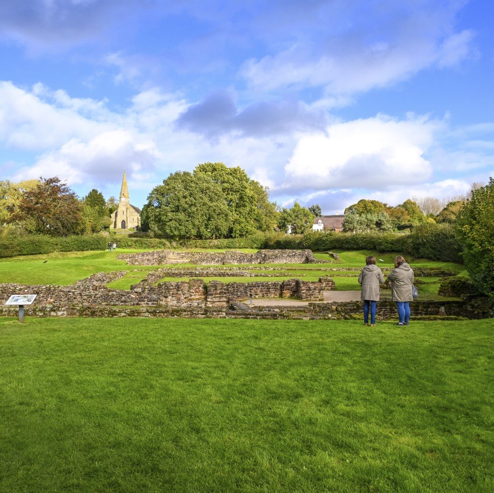 Photo of two people looking at the remains of Wall Roman Site on a cloudy day