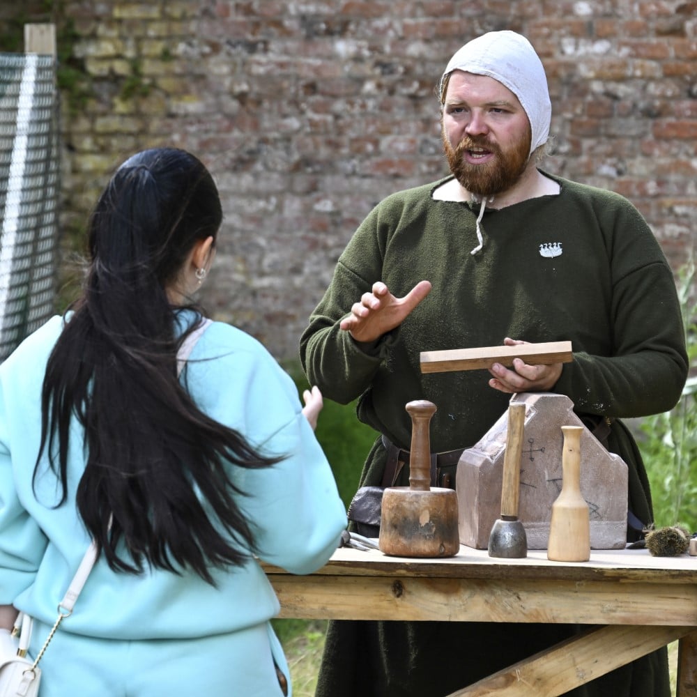 Photo of a person in medieval costume explaining about masonry to a visitor at Chester Castle