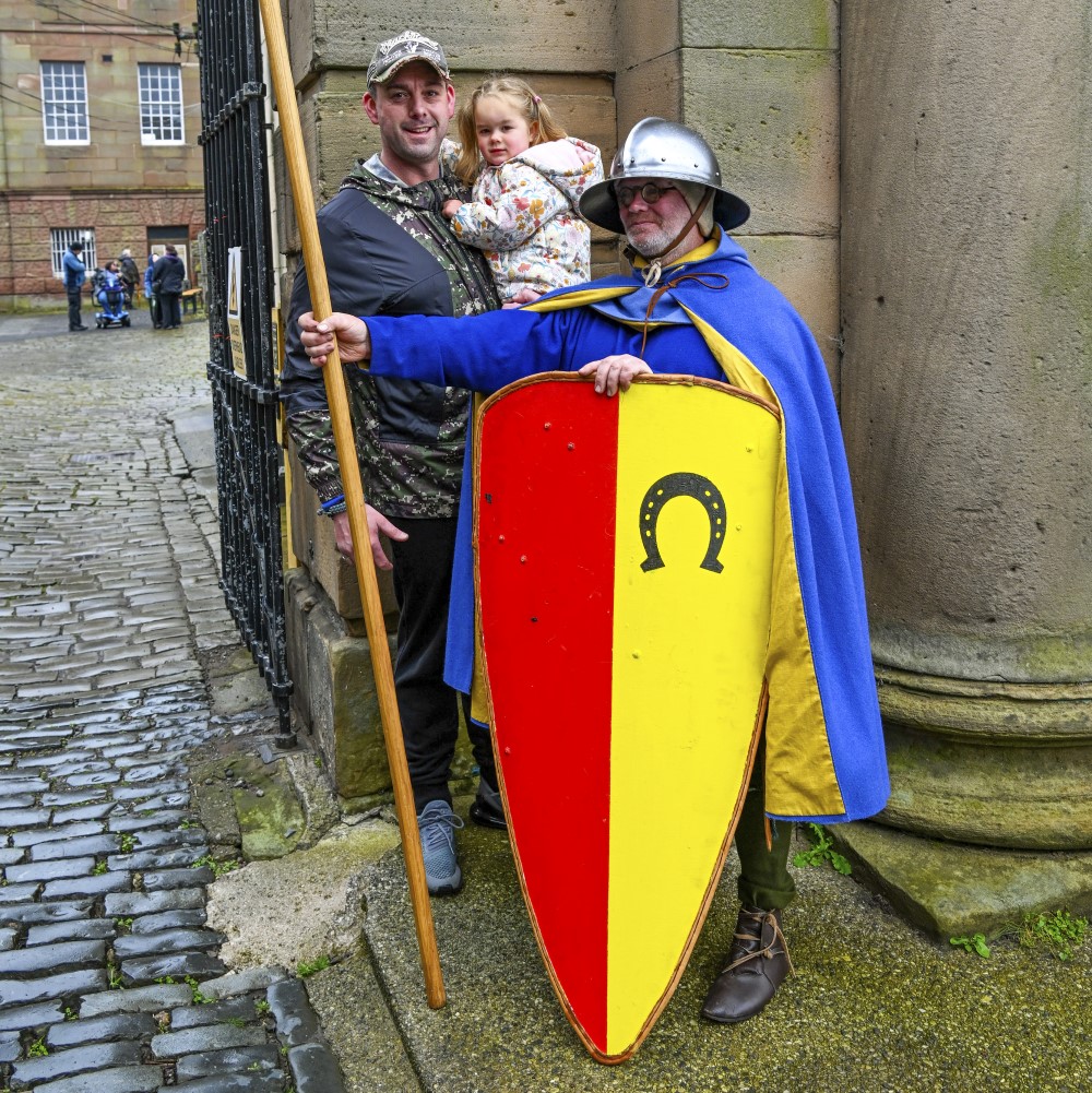 Photo of an adult holding a toddler and standing next to someone dressed as a medieval soldier at Chester Castle