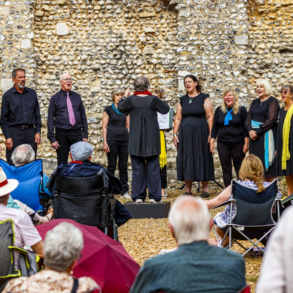 Photo of a choir singing to a seated crowd at a historical site