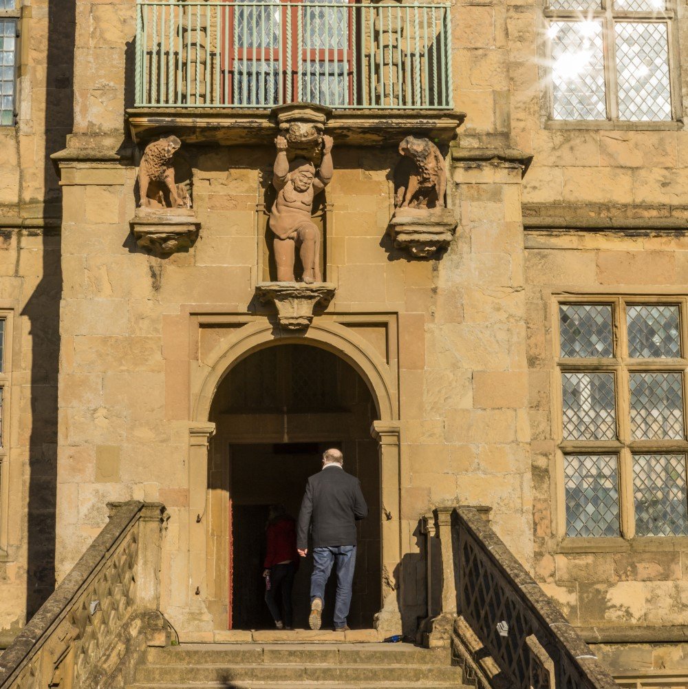 Photo of two people walking through a doorway at Bolsover Castle on a sunny day