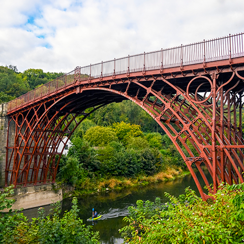Photo of Iron Bridge surrounded by trees with a kayaker paddling underneath the bridge