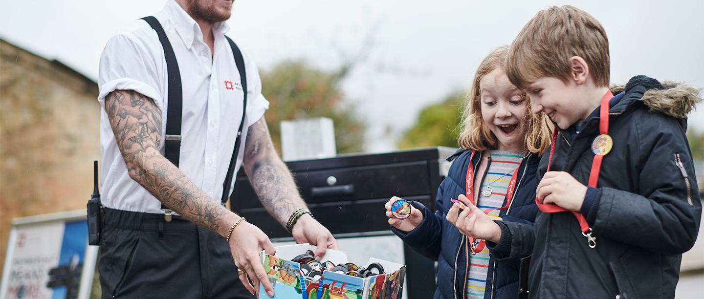 Image: two young members pick pop badges out from a box
