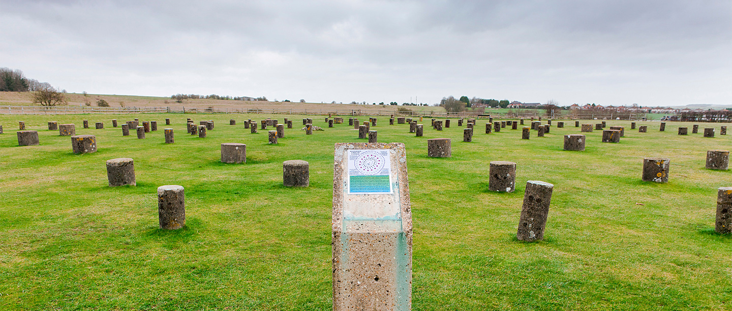 Short concrete posts poke out of a field (replicating previous wooden posts)