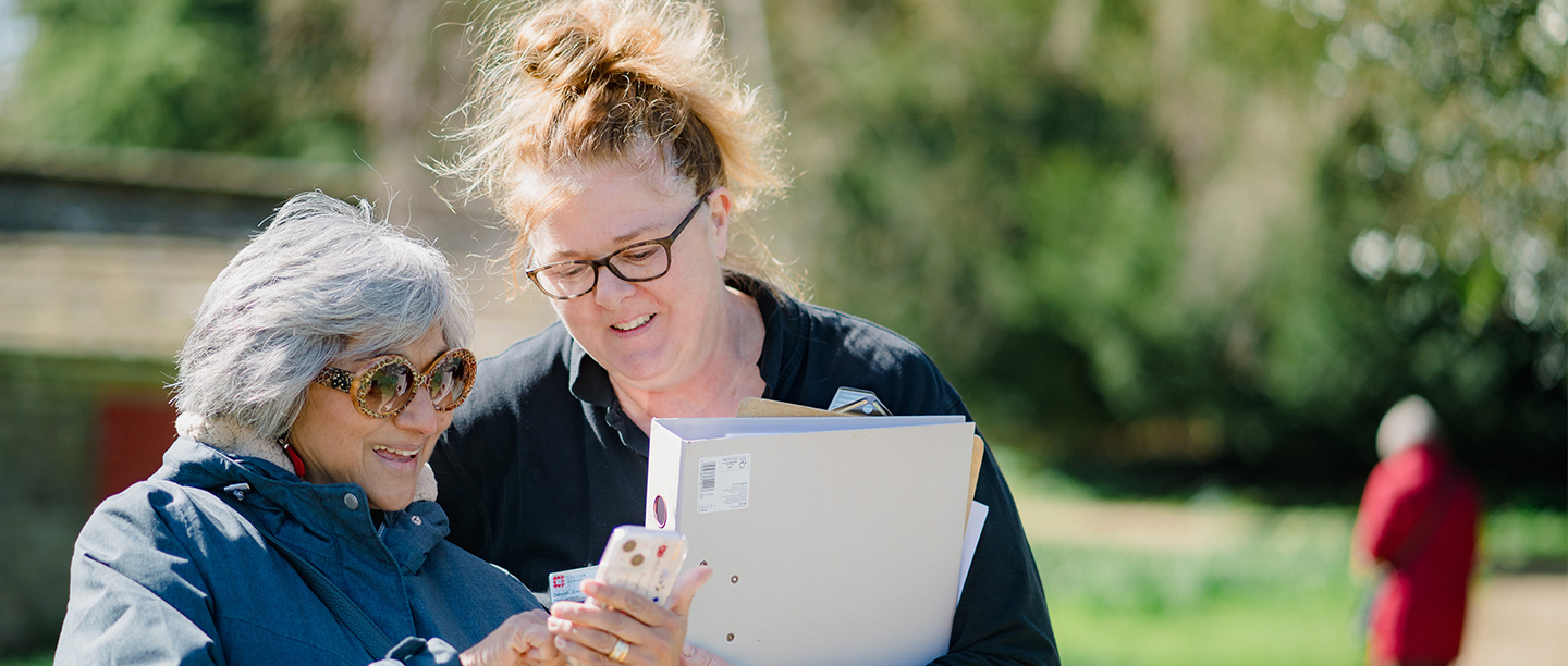 Image: a visitor shows her membership card to a staff member