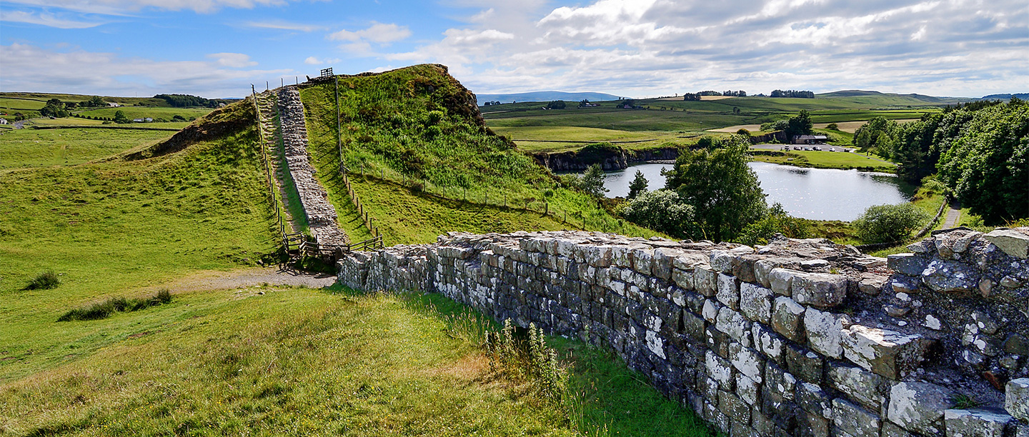 Waist-high Hadrian's Wall falls and rises with the landscape towards a cliff