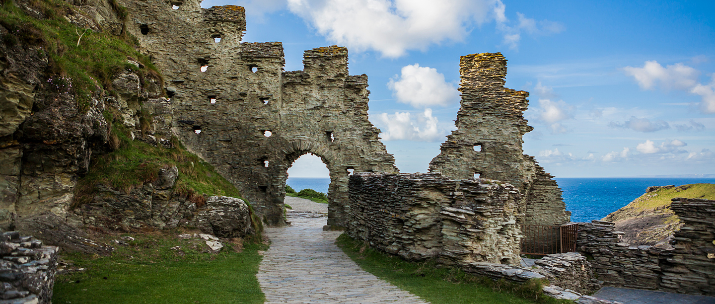 A view of the stone ruins of the medieval hall at Tintagel Castle with the sea in the background.