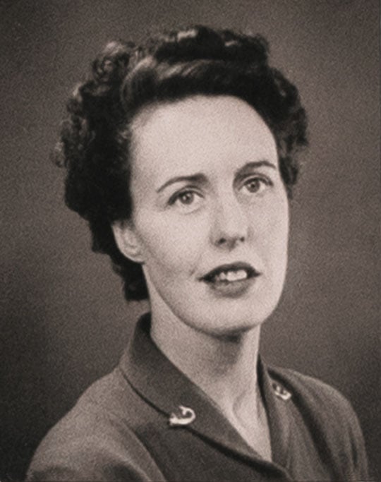 Black and white shoulder-height portrait of the novelist Barbara Pym showing her smiling with short dark curly hair and brooches on each lapel Black and white shoulder-height portrait of the novelist Barbara Pym showing her smiling with short dark curly hair and brooches on each lapel