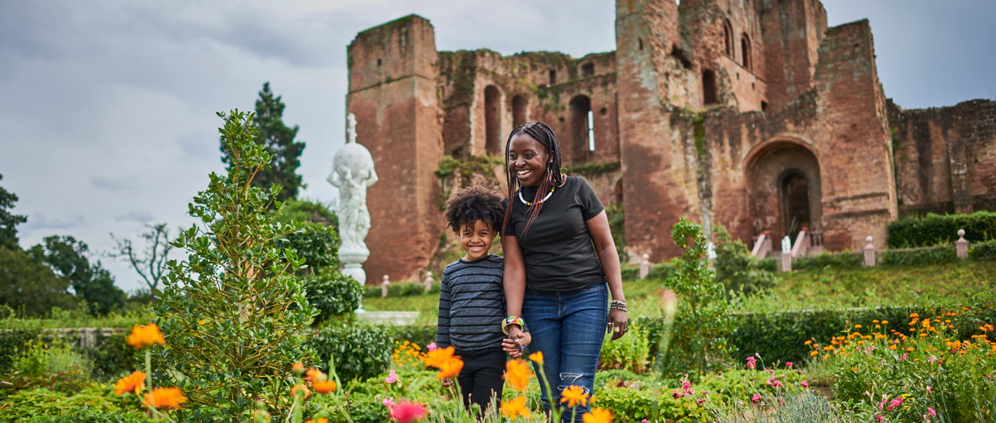 A woman and a child smile as they look at the flowers in the Elizabethan Garden at Kenilworth Castle