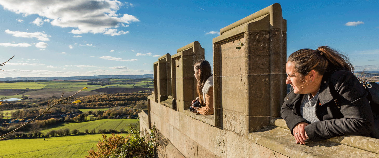Image: a woman and teenager look out from the battlements on top of Bolsover Castle