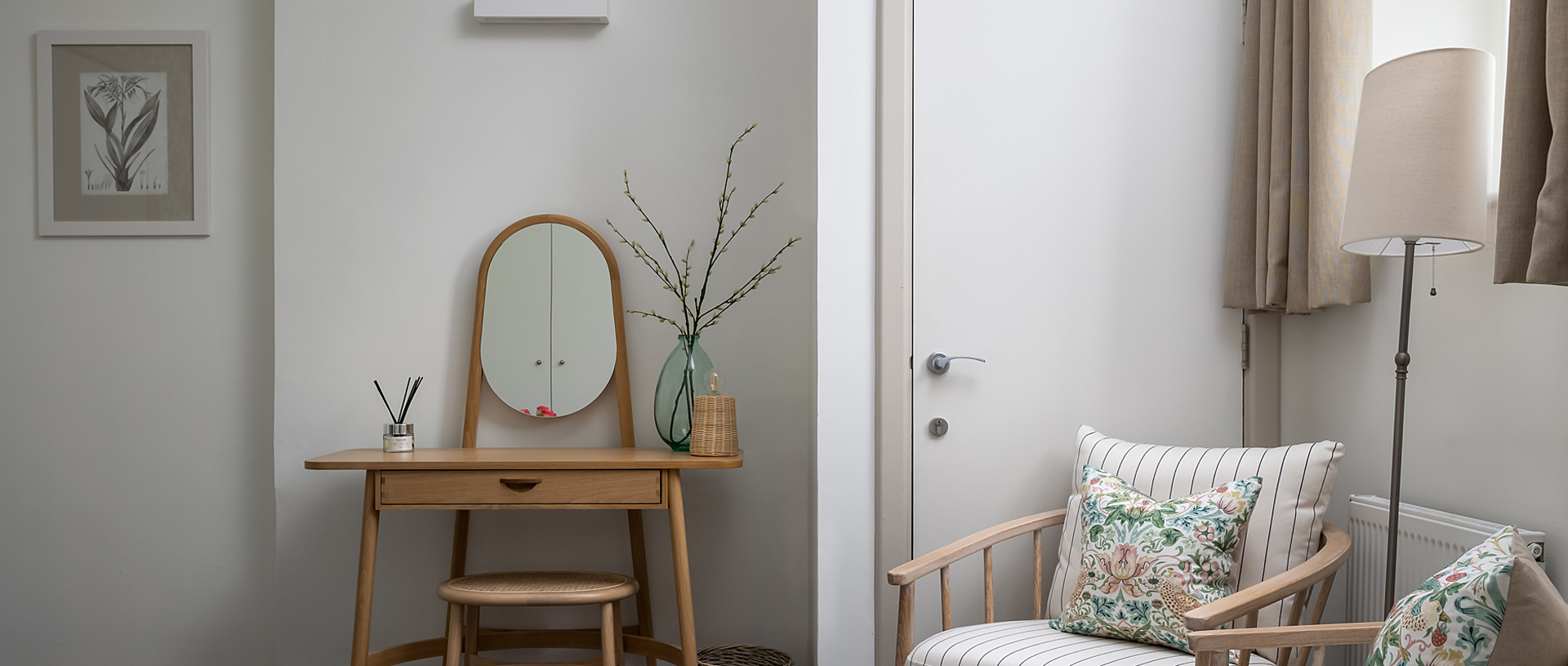 A wooden dressing table and wooden chairs in a cream coloured bedroom.