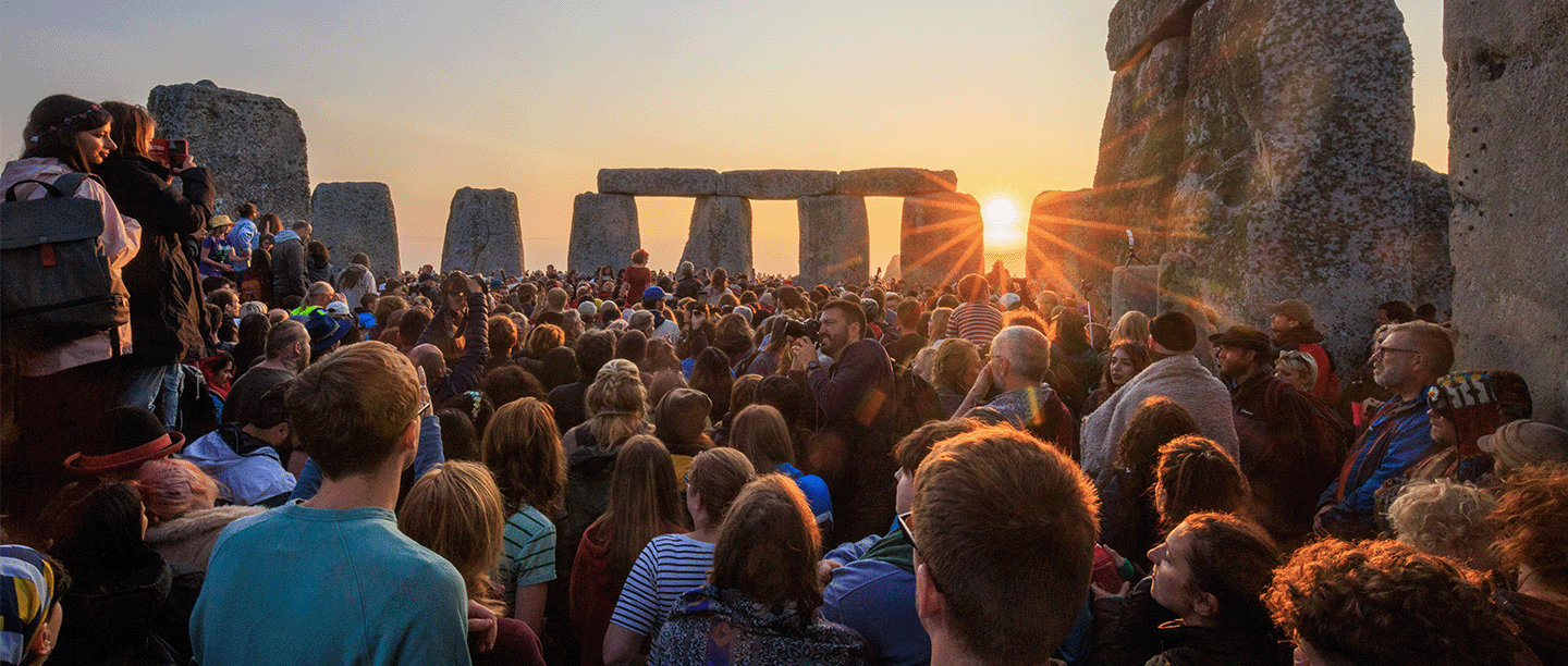 Photo of a large crowd of people watching the sun rise at the summer solstice at Stonehenge