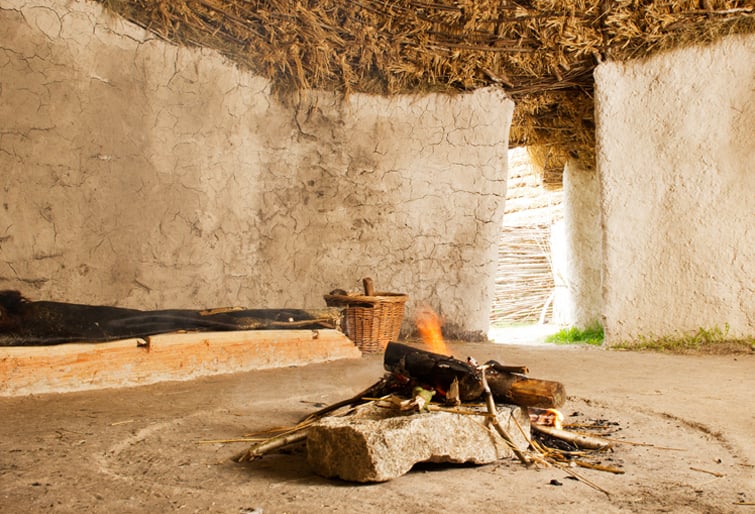 Image: Photo of a fireplace in the middle of a recreated Neolithic house at Stonehenge in WIltshire