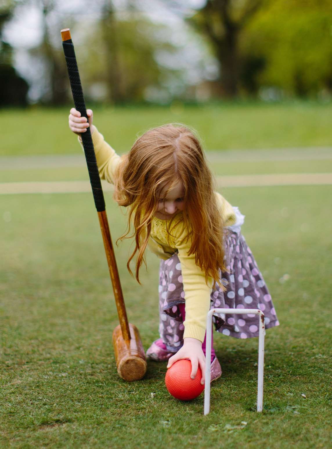 Image: A young child playing croquet
